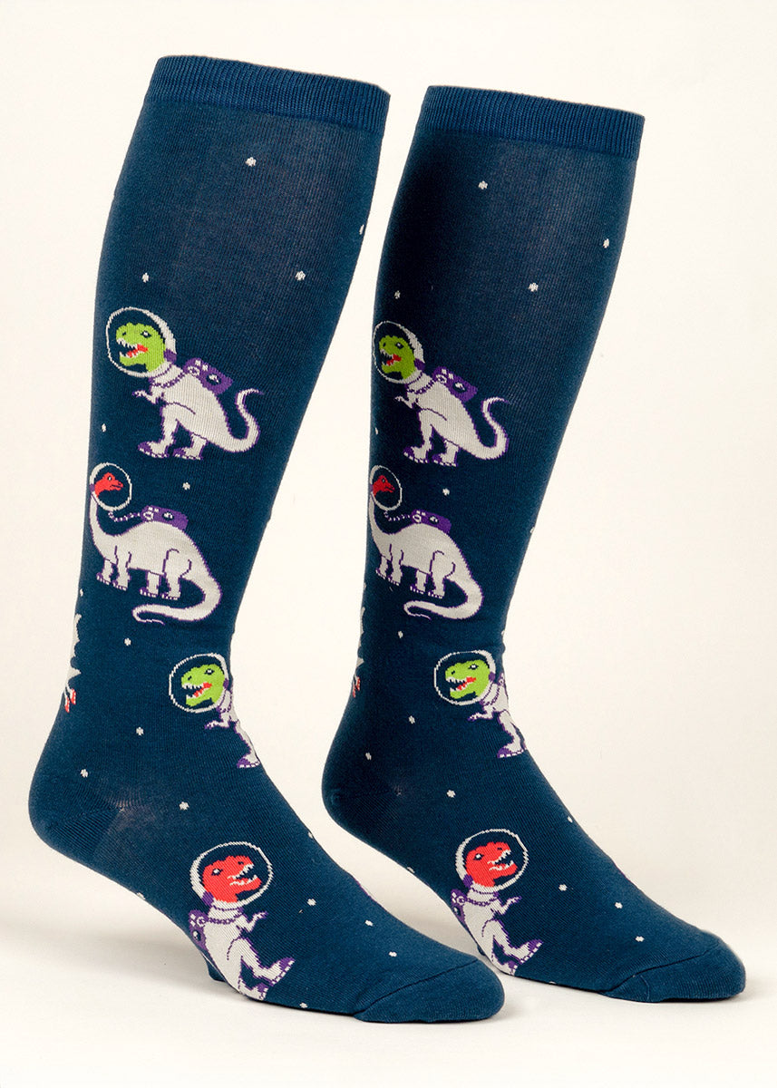 Dark blue knee socks for wide calves with an allover pattern of green and red dinosaurs dressed as astronauts floating around against a starry background.