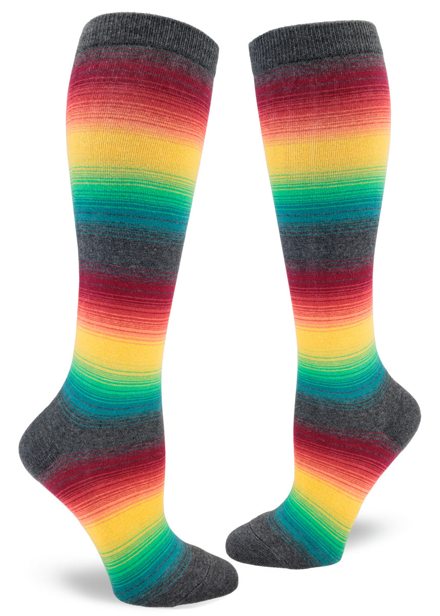 Knee-high socks for women with thin rainbow stripes set against a charcoal gray background.