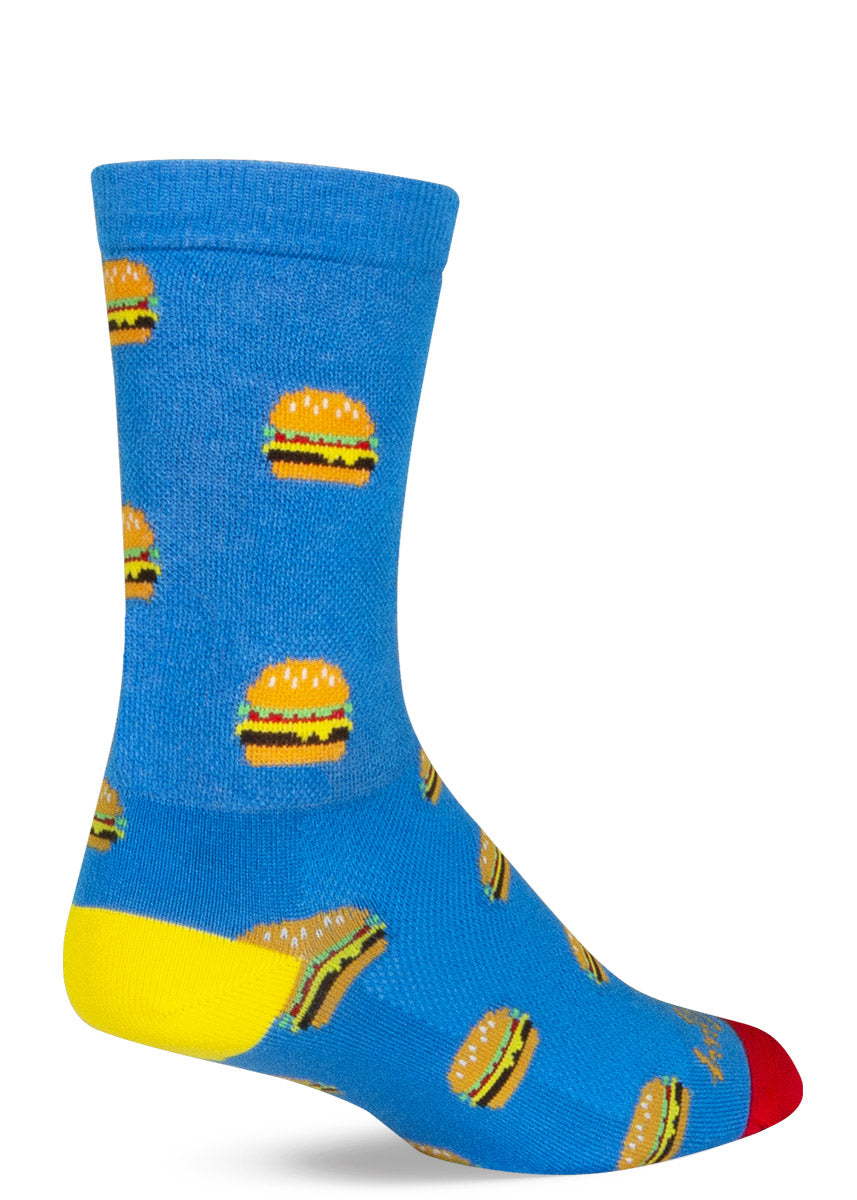 Blue athletic crew socks with a repeating pattern of cheeseburgers with a yellow heel and a red toe. 
