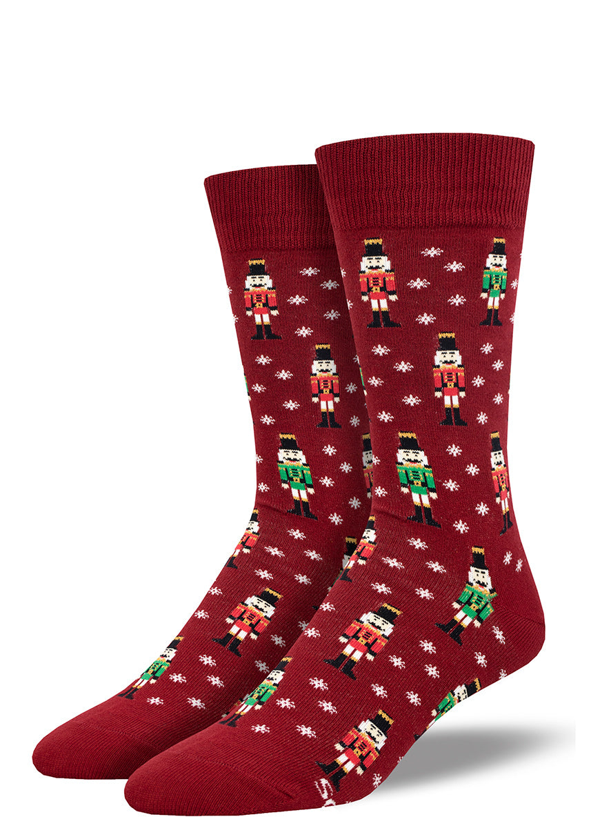 Maroon crew socks for men with an allover pattern of green and red nutcrackers as well as white snowflakes.