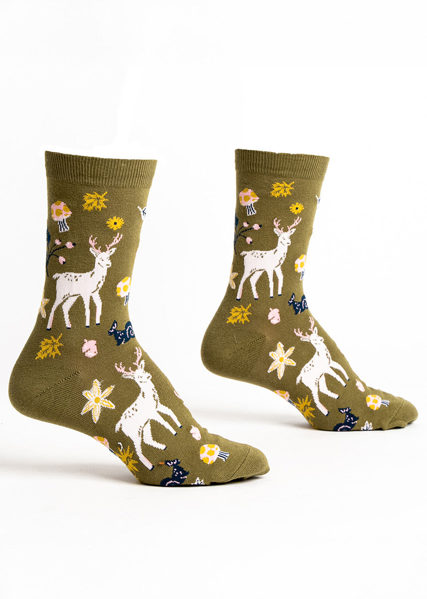 Green crew socks for women with an allover pattern of deer, mushrooms, and flowers.