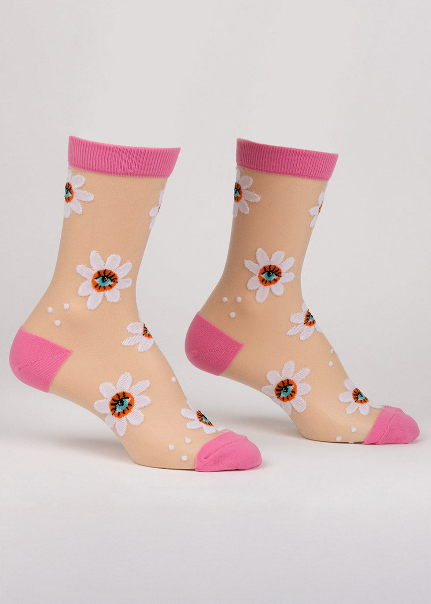 Sheer white crew socks for women with pink accents and an allover pattern of white daisies with an eyeball in the center.