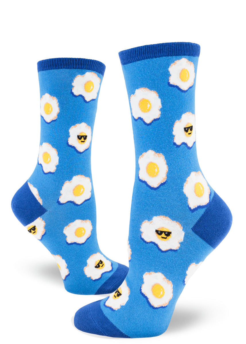 Blue novelty crew socks for women with an allover pattern of fried eggs, some of which have a face and are wearing sunglasses.