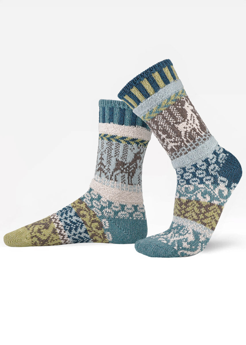 Mismatched socks feature patterns in blues, greens, whites, and browns with a mountain goat design.