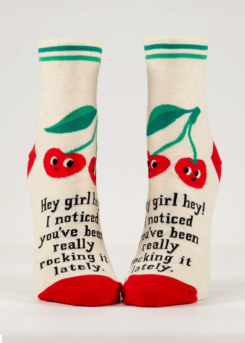 White ankle socks for women that say, &quot;Hey girl hey! I noticed you&#39;ve been really rocking it lately&quot; on them and feature a design of two big red cherries with smiley faces and green stripes on the cuff. 