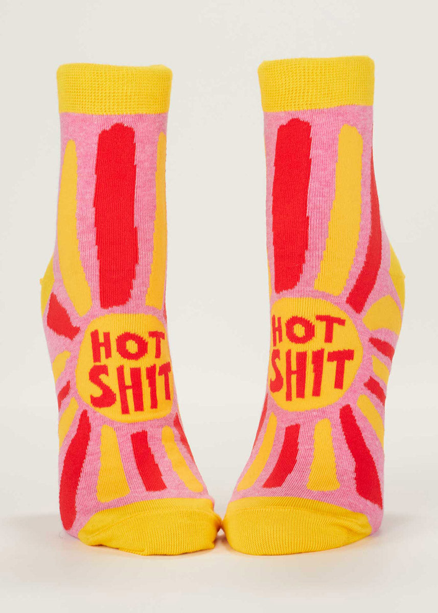 Ankle socks for women with a bright pink background and the words “HOT SHIT” surrounded by a sunburst of colorful stripes. 