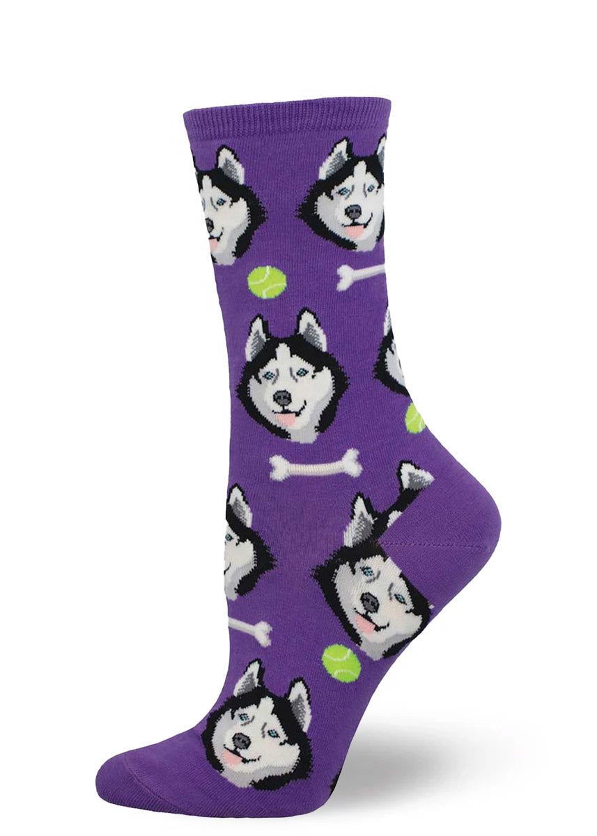 Purple crew socks for women with an allover pattern of husky dog faces, bones, and tennis balls. 