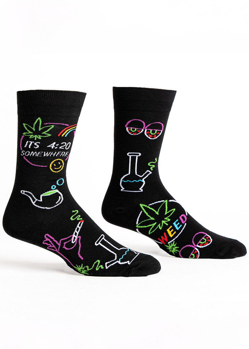 Black novelty crew socks for men with various marijuana-related images resembling neon lights and the phrase &quot;It&#39;s 4:20 Somewhere.&quot; 