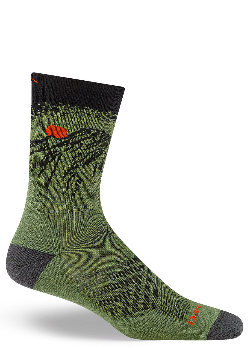 Green and black hiking crew socks for men with a mountain vista design, including a bright orange sun. 