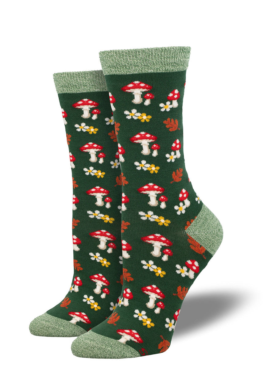 Green bamboo crew socks for women with an allover pattern of red toadstool mushrooms, white and yellow flowers, and orange fall leaves. 