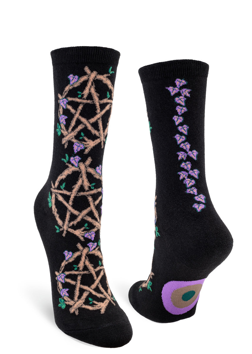 Black crew socks for women with five-pointed star symbols made from vines sprouting green and purple leaves that climb up the front, and a purple vine winding its way up your ankles on the back. 