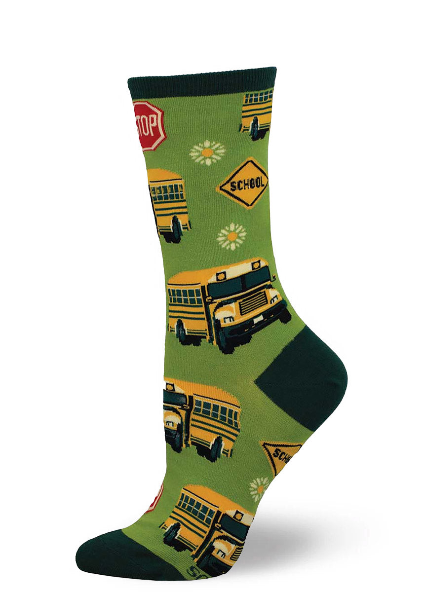 Green crew socks for women with an allover pattern of yellow school buses, stop signs, and yellow daisies. 