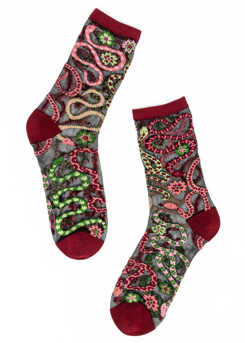 Sheer black crew socks for women with an allover pattern of intertwined snakes in shades of red, pink, and green as well as floral designs.