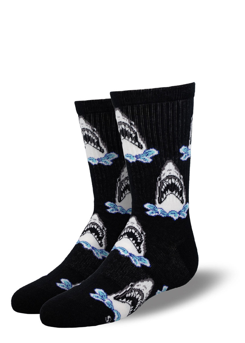  Black athletic crew socks for kids with an allover pattern of sharks opening their jaws while coming out of the water. 