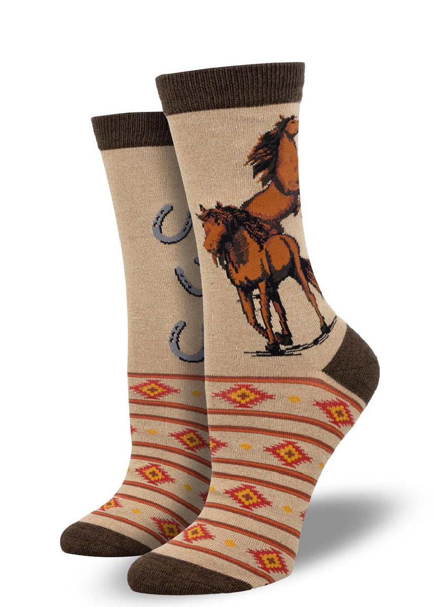 Light brown crew socks for women with two brown horses on one side of the calf and horseshoes on the other with a red and yellow southwestern style pattern on the foot.