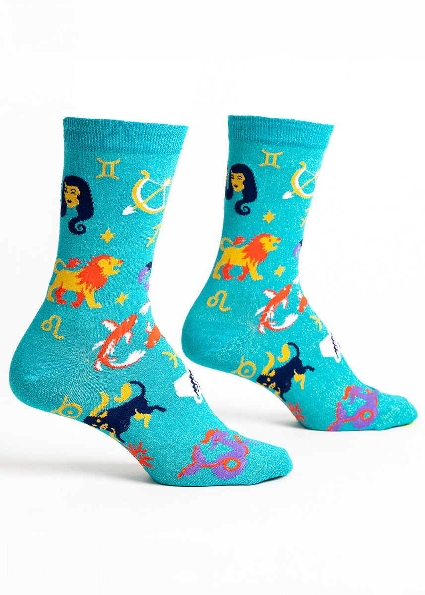 Teal crew socks for women with gold shimmer and a pattern of zodiac symbols. 